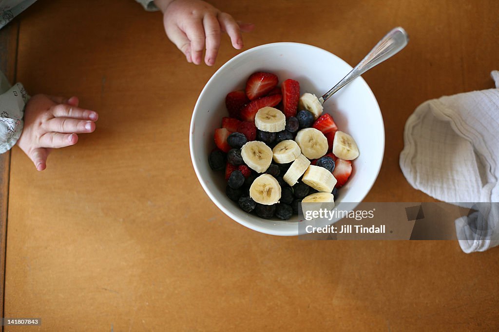 Toddler reaches for bowl of fruit