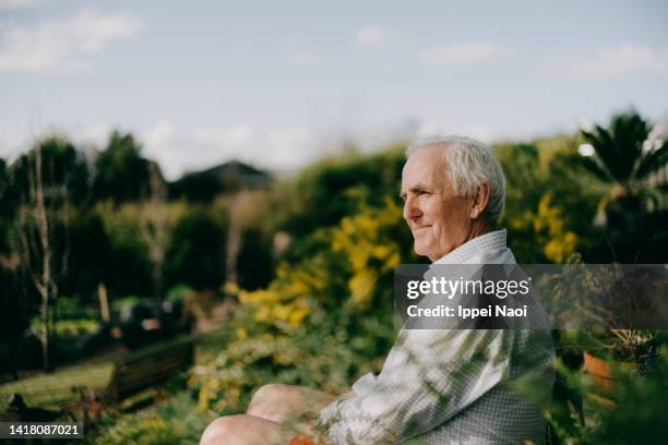 senior man sitting in garden and looking at view - smiling 70 stock-fotos und bilder