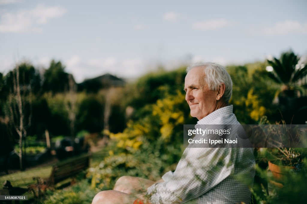 Senior man sitting in garden and looking at view