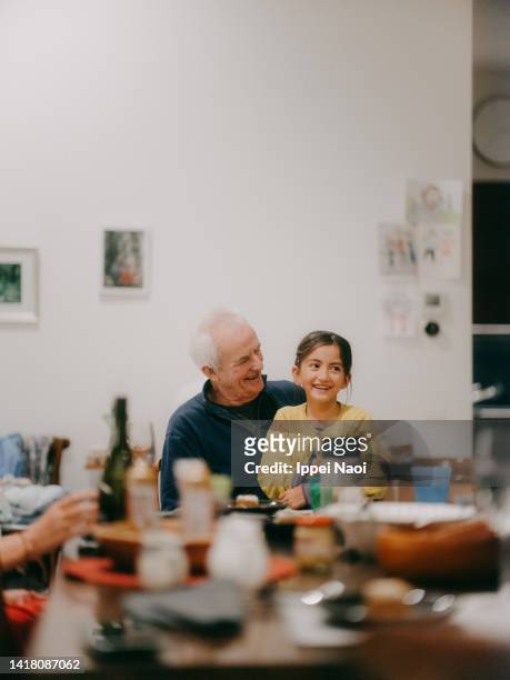 happy grandfather and granddaughter at dinner table - eurasian ethnicity stock pictures, royalty-free photos & images