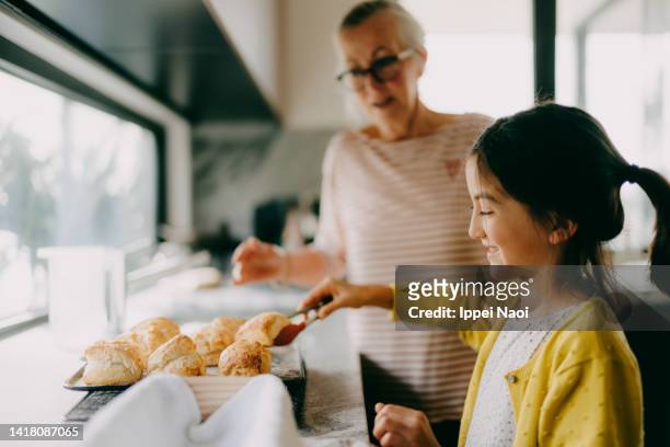 young girl in kitchen with her grandmother - scone stock pictures, royalty-free photos & images