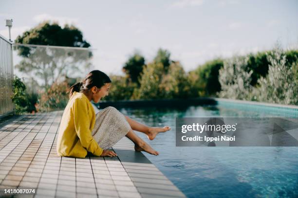 young girl sitting by pool at home - eurasische herkunft stock-fotos und bilder