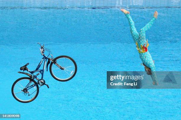 Performer falls with a bicycle after riding it off the 10m diving platform during day two of the FINA/Midea Diving World Series 2012 Beijing Station...