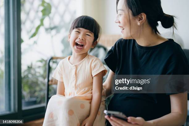 young asian mother and lovely little daughter having a great time together. mother and daughter spending time at home, both of them are smiling joyfully. bonding between mother and daughter. family lifestyle. love and care concept - chinese mothers day foto e immagini stock