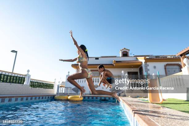 two brothers jump into the pool on a summer day having fun - wide angle house stock pictures, royalty-free photos & images
