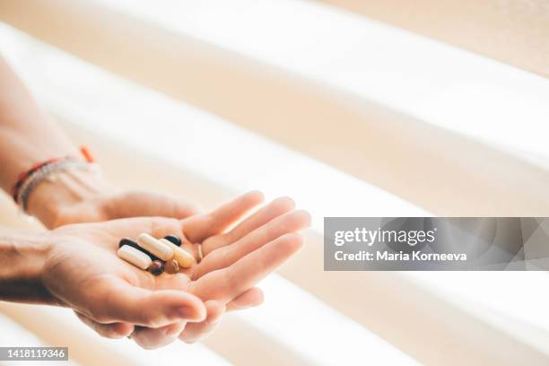 woman taking vitamins and supplements. - hand holding several pills photos et images de collection