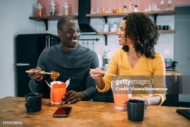 smiling couple having lunch together at home. - chinese cuisine stock pictures, royalty-free photos & images