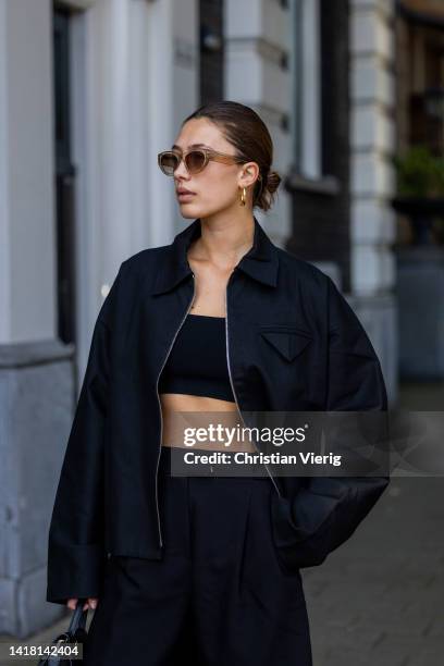 Chelsey Weimar wears Shoes / Prada, Black shorts / Shona Joy, Black top / Shona Joy, Jacket / Bottega Veneta, Sunglasses / Chimi, Celine bag during a...