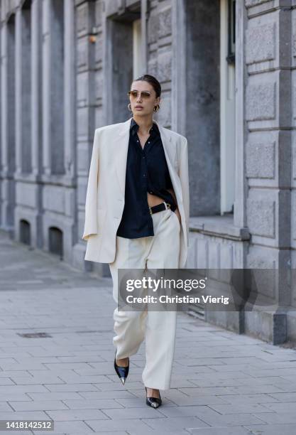 Chelsey Weimar wears Shoes / Prada, Pants / Agreeg, Black blouse / Massimo Dutti, White blazer / Nanushka, Sunglasses / Ray Ba during a street style...