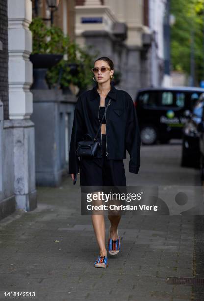 Chelsey Weimar wears Shoes / Prada, Black shorts / Shona Joy, Black top / Shona Joy, Jacket / Bottega Veneta, Sunglasses / Chimi, Celine bag during a...