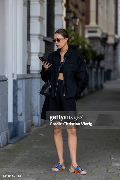 Chelsey Weimar wears Shoes / Prada, Black shorts / Shona Joy, Black top / Shona Joy, Jacket / Bottega Veneta, Sunglasses / Chimi, Celine bag during a...