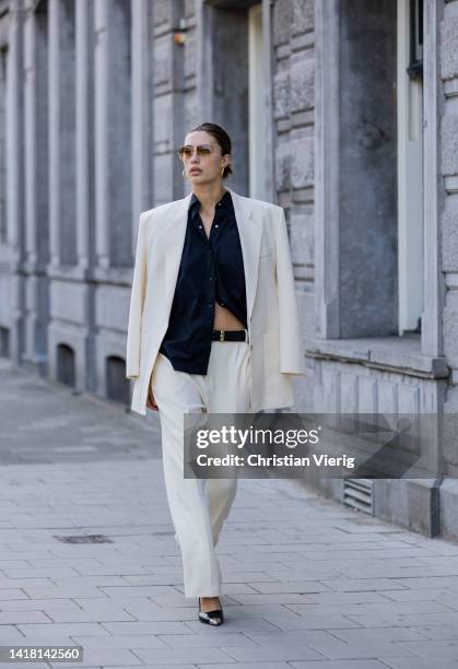 Chelsey Weimar wears Shoes / Prada, Pants / Agreeg, Black blouse / Massimo Dutti, White blazer / Nanushka, Sunglasses / Ray Ba during a street style...