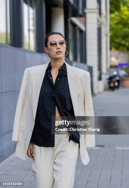 Chelsey Weimar wears Shoes / Prada, Pants / Agreeg, Black blouse / Massimo Dutti, White blazer / Nanushka, Sunglasses / Ray Ba during a street style...