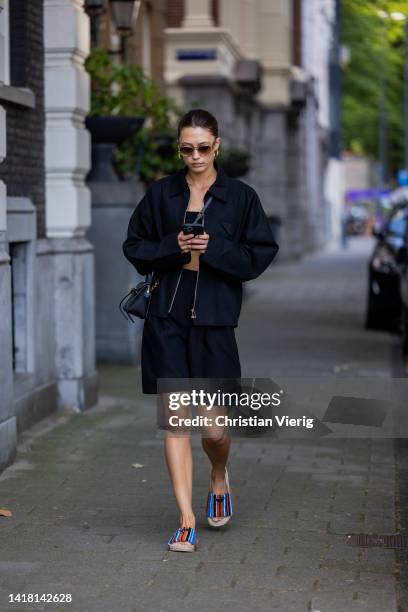 Chelsey Weimar wears Shoes / Prada, Black shorts / Shona Joy, Black top / Shona Joy, Jacket / Bottega Veneta, Sunglasses / Chimi, Celine bag during a...