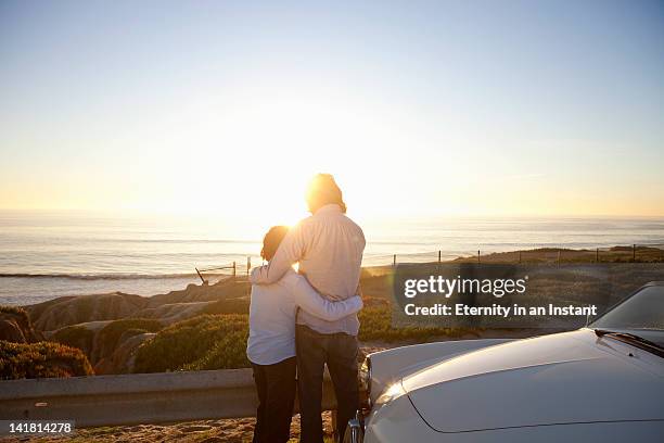 father and son looking at ocean with sun flare - young man asian silhouette stock pictures, royalty-free photos & images