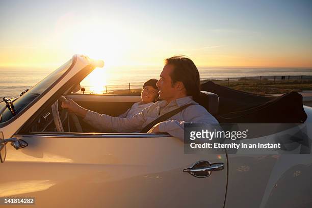 father and son driving by ocean in convertible car - young man asian silhouette stock pictures, royalty-free photos & images