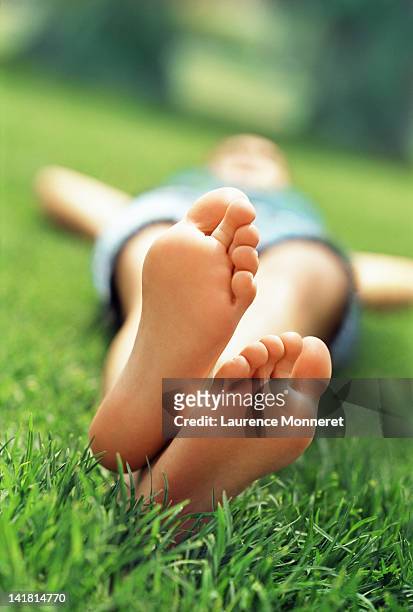 young woman with crossed feet, lying  in grass - female soles stock-fotos und bilder