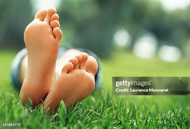 young woman lying in grass with crossed feet - female soles stock-fotos und bilder