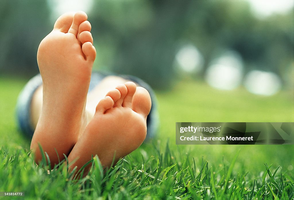 Young woman lying in grass with crossed feet