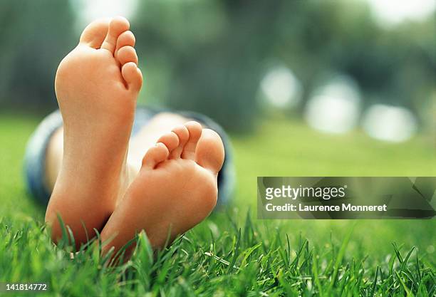young woman lying in grass with crossed feet - foot stockfoto's en -beelden