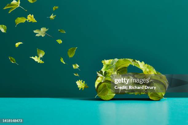 a car made of leaves with an exhaust trail of leaves - green colour car stock pictures, royalty-free photos & images