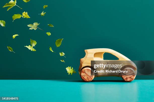 a wooden car with an exhaust trail of leaves - car emissions stock-fotos und bilder