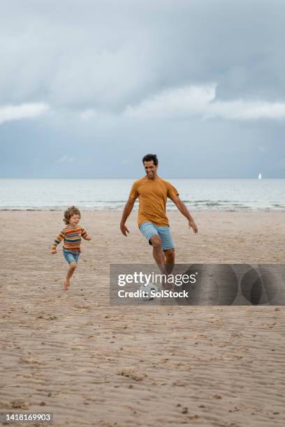playing football by the sea - kicking sand stock pictures, royalty-free photos & images