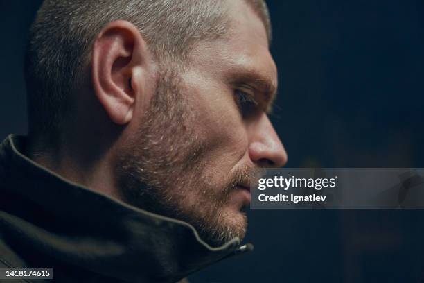 close-up profile of a prisoner on a dark background - interrogation stock pictures, royalty-free photos & images