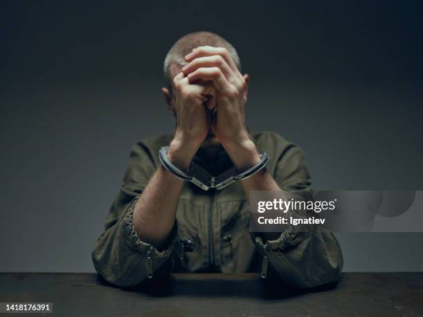 a man in handcuffs on a gray background in professional studio light - suspicion stock pictures, royalty-free photos & images