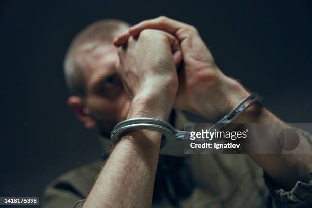 close-up of hands in handcuffs on a blurred background - criminal offense stock pictures, royalty-free photos & images