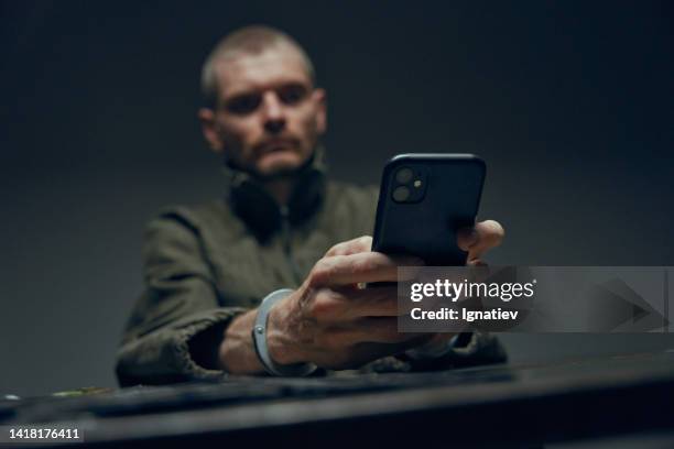 hands in handcuffs with a smartphone in the foreground, with a defocused background with a man, who's hands we see - phone interview event stock pictures, royalty-free photos & images