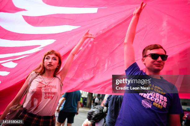 People stand under a vast CWU flag during a strike action protest outside the Mount Pleasant Royal Mail sorting office on August 26, 2022 in London,...