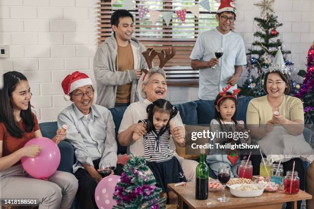 senioren- und enkelgruppe der familie, die spaß hat, weihnachten und neujahrsfeier zu hause zu feiern - 25 30 years old asian stock-fotos und bilder