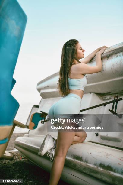 belleza femenina relajada que muestra un cuerpo curvilíneo mientras se relaja en botes de playa - beach bum fotografías e imágenes de stock