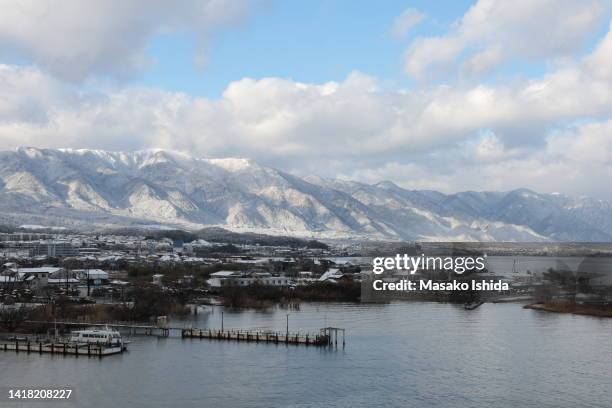 aerial winter view of lake biwa (lake biwako) and lakeside old town with snow covered hira mountains in the background. dramatic cloud formations in the sky. - omi stock pictures, royalty-free photos & images