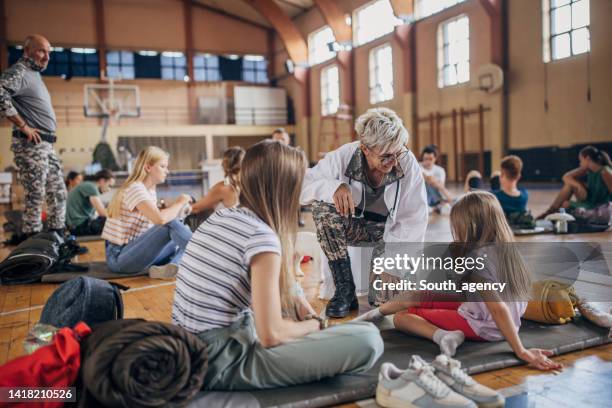 army doctor with civilians after natural disaster - humanitarian aid stock pictures, royalty-free photos & images