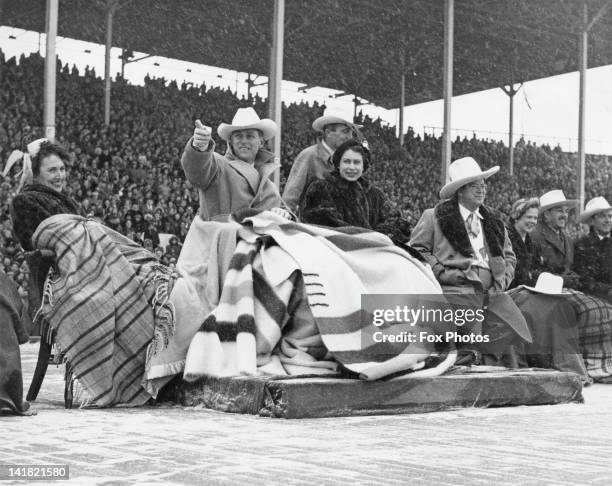 Princess Elizabeth and Prince Philip brave a snowstorm to watch a stampede at Calgary exhibition grounds, Canada, 24th October 1951. Next to the...