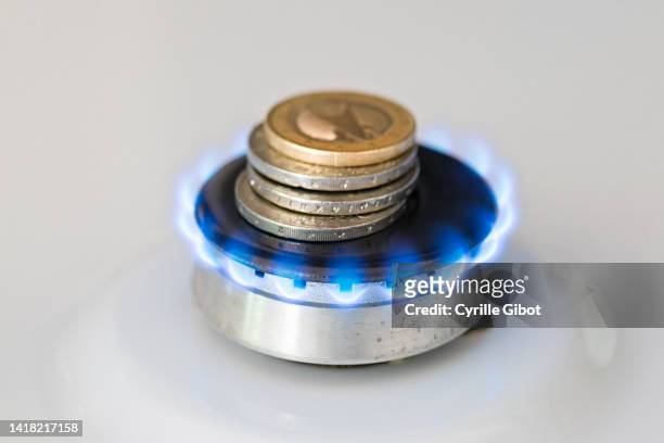 a lit gas burner burns money with a blue flame - concept illustrating rising gas prices - geldstrafe stock-fotos und bilder