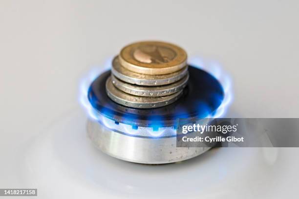 a lit gas burner burns money with a blue flame - concept illustrating rising gas prices - energie industrie stockfoto's en -beelden