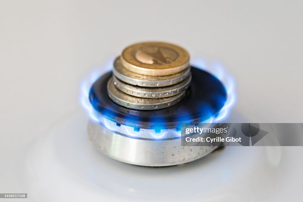 A lit gas burner burns money with a blue flame - Concept illustrating rising gas prices