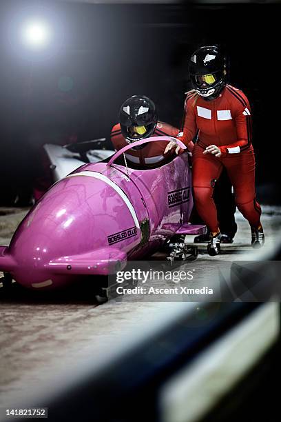 bobsled racers push sled to start line,competition - bobrennschlitten stock-fotos und bilder