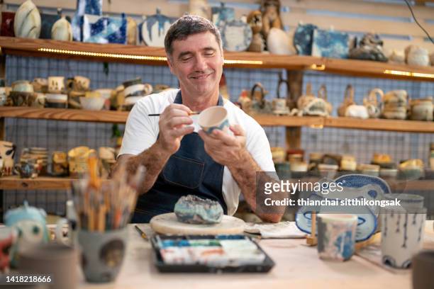 man potter painting a cup in his pottery studio. - painting art product stock pictures, royalty-free photos & images