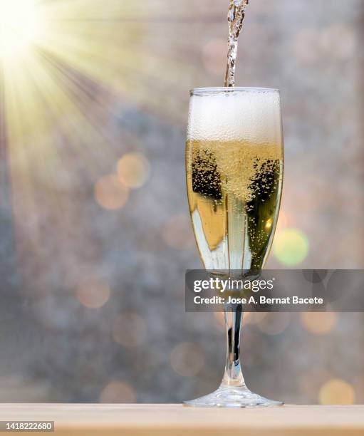 close-up fill a glass of champagne glass illuminated by sunlight. - champagner gläser mit flasche unscharfer hintergrund stock-fotos und bilder