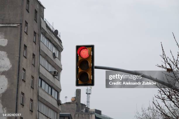 traffic light close-up with a red signal. traffic light on the background of a residential multi-storey high-rise building, in an old residential area. traffic rules. prohibited traffic light signal. - feu rouge feu de signalisation pour véhicules photos et images de collection
