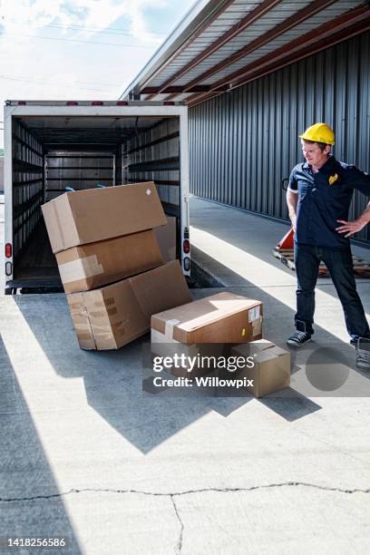 tired loading dock worker staring down at damaged cardboard cartons - wrong package stock pictures, royalty-free photos & images