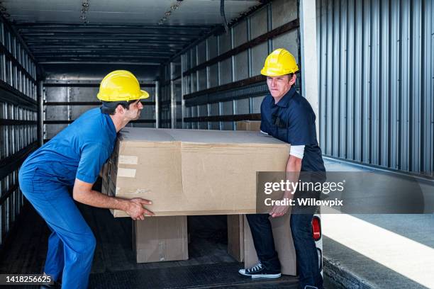 two loading dock workers carrying heavy cardboard box - pick-up imagens e fotografias de stock