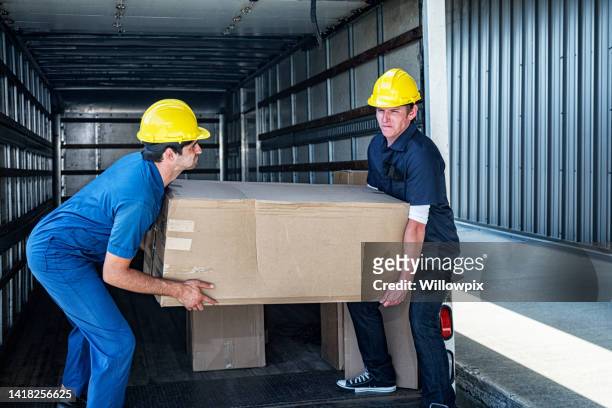 two loading dock workers carrying heavy cardboard box - picking up 個照片及圖片檔