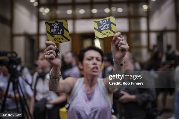 Woman holds up leaflets calling on customers to refuse to pay their energy bills during a demonstration outside Ofgem's headquarters in Canary Wharf...