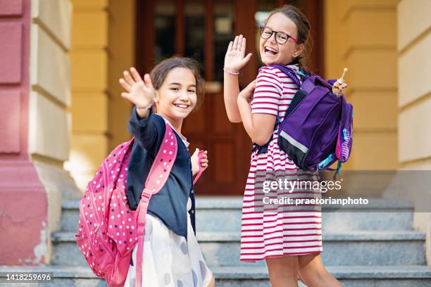 schoolgirls are waving hands and entering a school - first day of school bildbanksfoton och bilder