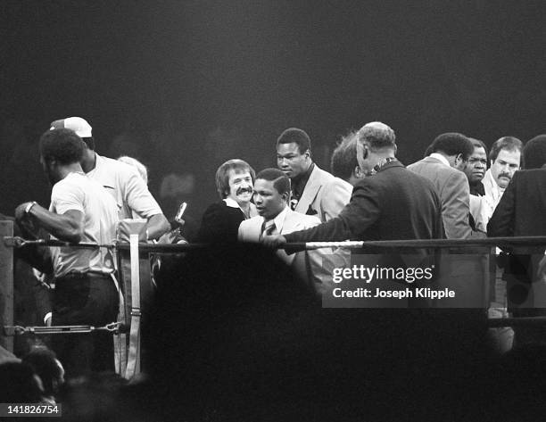 View of people in the ring, including Sonny Bono and Larry Holmes, during a Heavyweight Championship boxing match between American boxer Muhammad Ali...